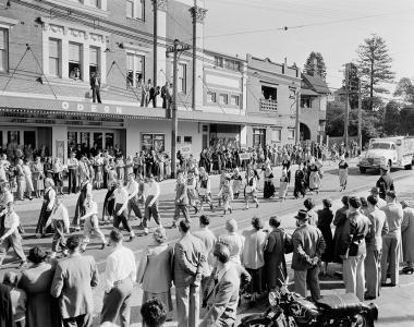 People marching on a street outside a pub.