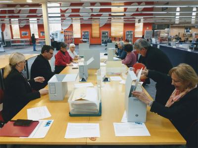 Volunteers working with paper records stored in cardboard archival boxes.