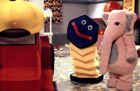 People wearing toy costumes: a truck, concertina and pink elephant.