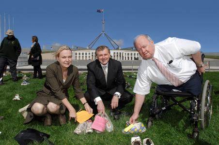 MPs holding shoes, crouch on the lawn before Parliament House
