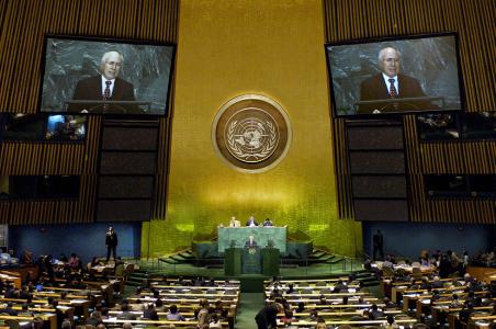 John Howard on large video screens beside an imposing backdrop for UN General Assembly