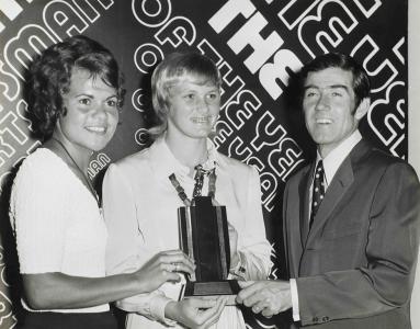 3 sports-people holding a trophy