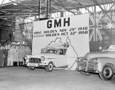 A holden sedan drives through a banner to celebrate completion of the 500,000th car.