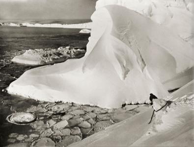 A man secured with rope stands near the edge of the ice.