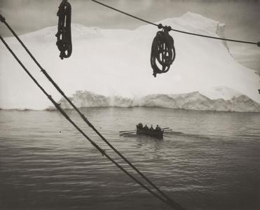 A row boat approaching an iceberg.