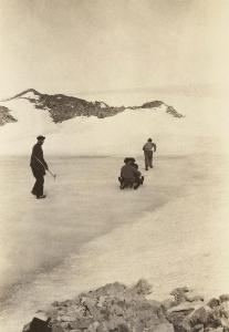 2 men being towed across the ice on a sled.