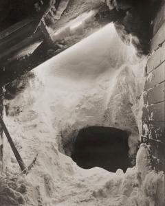 Snow being cleared from beside a hut.