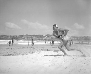 A surf lifesaver runs toward the water.