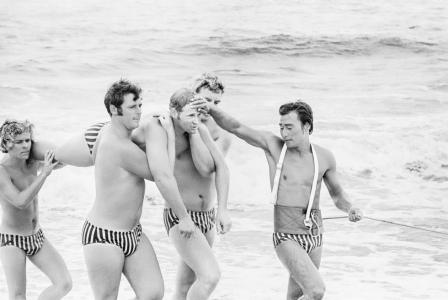 Surf lifesavers carrying a colleague while a practicing a rescue