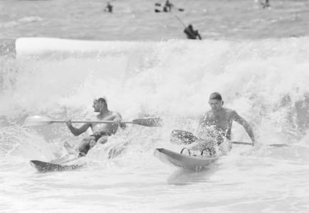 2 life saver riding a wave on paddle boards