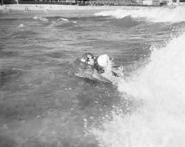 A surf lifesaver using swims using a towing technique to help a woman to shore