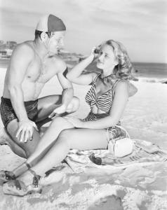 Lifesaver talking with a woman sitting on the sand