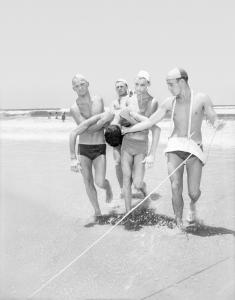 4 lifesavers carrying a man across the sand.