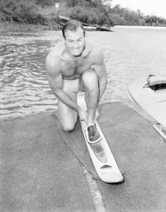 Brian kneeling on a jetty attaches his water ski