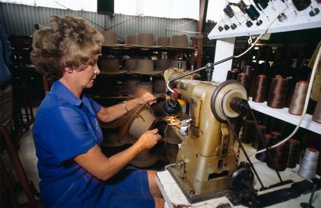 A woman sewing a hat band onto an Akubra hat