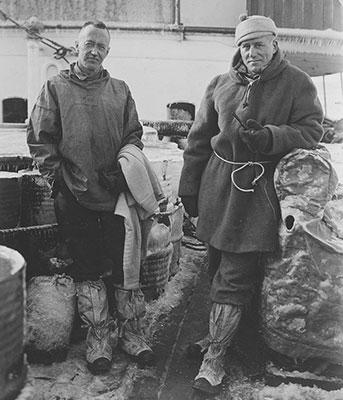 2 men standing on the deck of a ship.