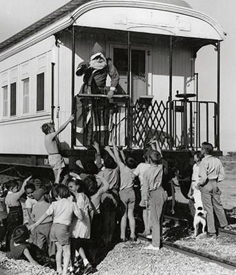 Santa on a train surrounded by children.