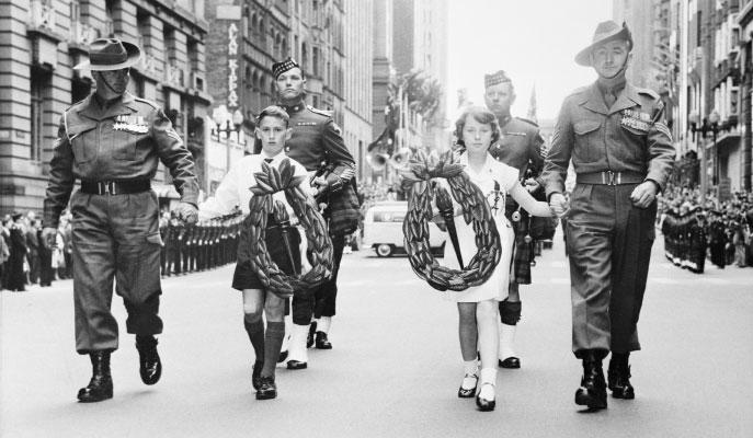 4 soldiers escorting 2 children who are both holding wreaths.